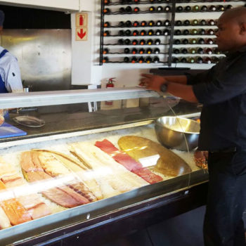 Vitrine e garçom explicando os diferentes tipos de peixe